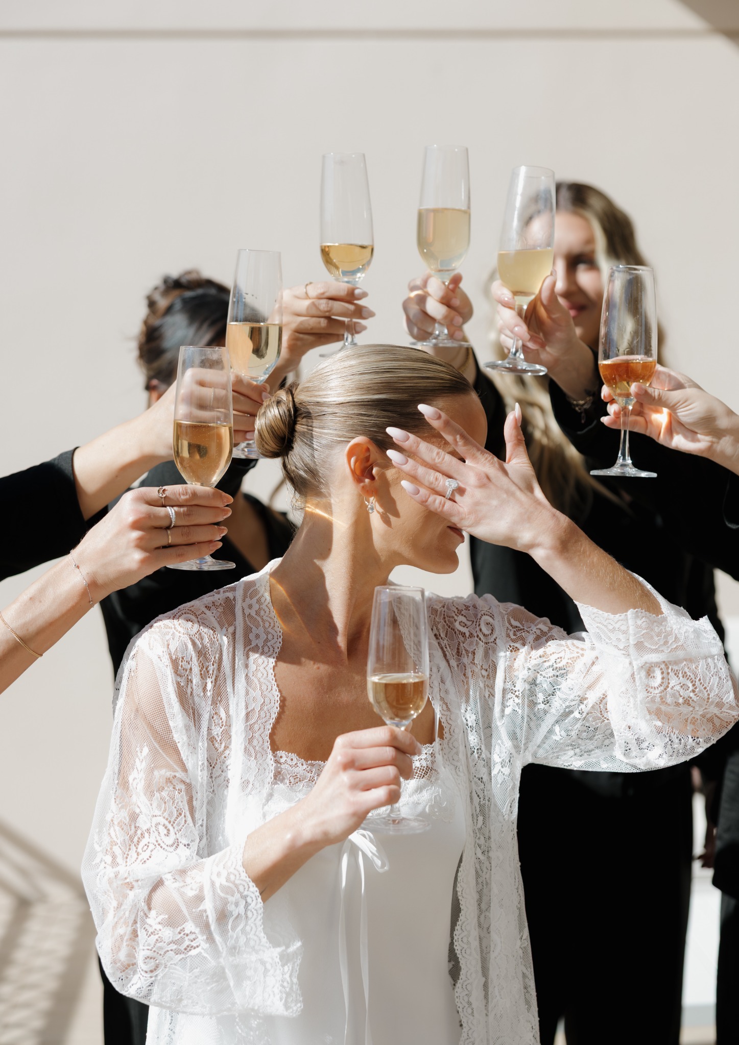 Bride surrounded by friends raising champagne glasses