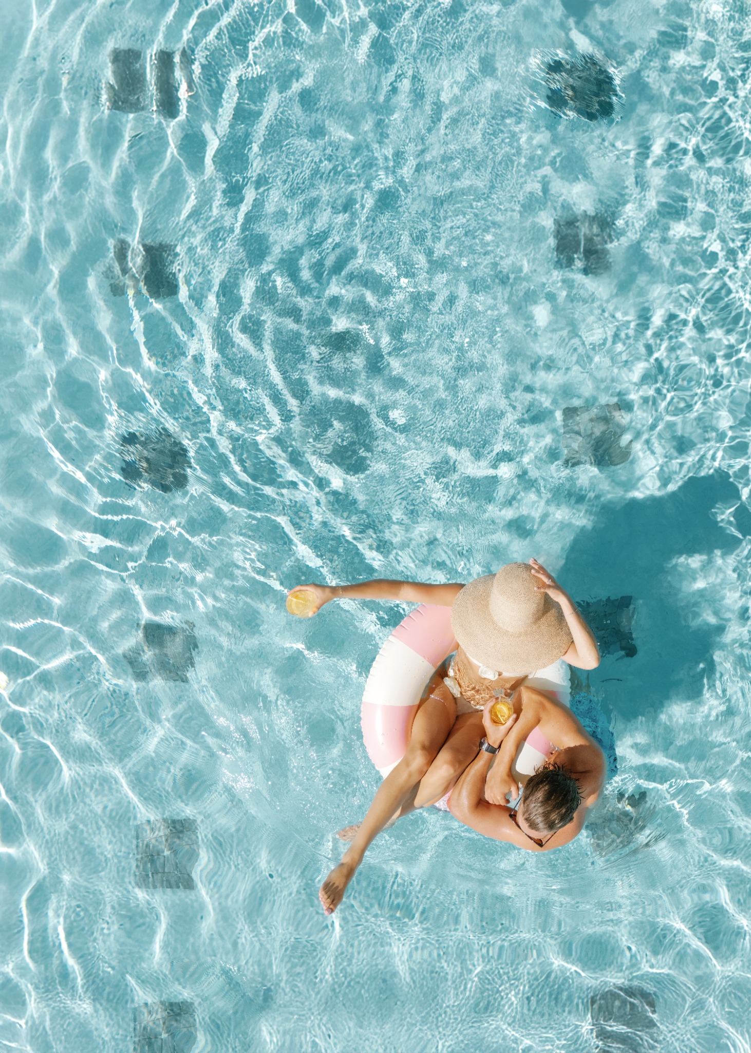 Couple floating together in a blue swimming pool